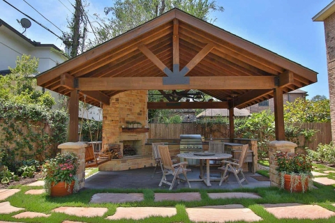 A nice outdoor gazebo are with an outdoor grill and nice outdoor furniture.